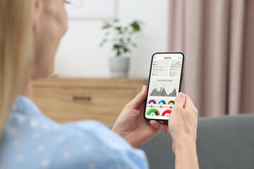 Woman monitoring smart meter readings on mobile phone at home, closeup