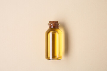Essential oils in bottle on beige background, top view