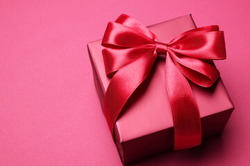 Gift box with bow on pink background. Space for text