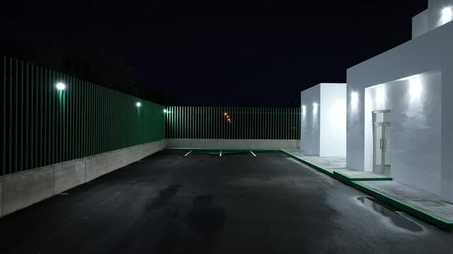 Infraestructura de edificio blanco y cajones de estacionamiento con alumbrado 