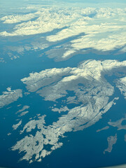 From the aircraft, panoramic views through a passenger window reveal stunning white-capped...