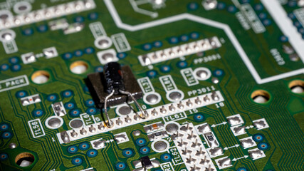 Obraz premium A green circuit board with a black component on it