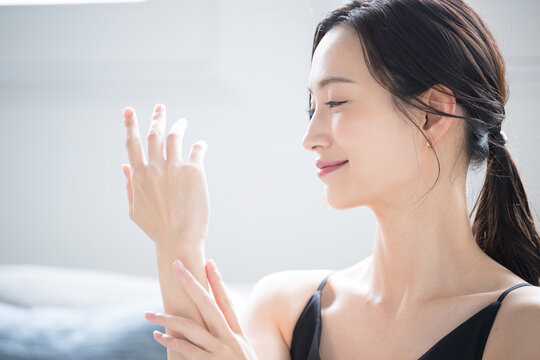 冬の手荒れや乾燥に使えそうなクリームを塗る美しい女性　手のイメージのクローズアップの横顔