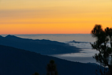 Obraz premium Stunning sunset view over mountain range with clouds filling the valley in serene evening light