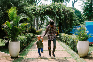 A father and his child running together in a city square