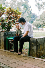 A father and his child sitting and chatting in a city square