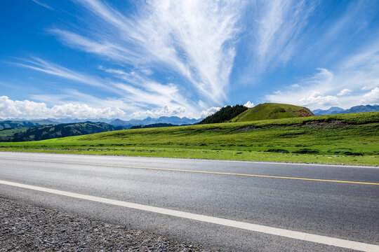 Asphalt highway road and green grasslands with mountain natural landscape in summer. Road trip.