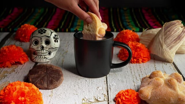 Hand of a mexican woman soaking bread of the dead in a cup of hot chocolate, Mexican food dia de muertos