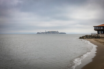 Obraz premium View of Alcatraz Island from Crissy Field, San Francisco, California, showcasing the historic prison shrouded in a tranquil, cloudy seascape.
