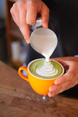 An Artisan Barista Skillfully Preparing a Matcha Latte with an Intricate Milk Foam Design