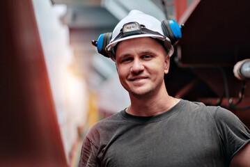 Portrait Of Smiling Fit Young Worker In Helmet And Ear Protectors