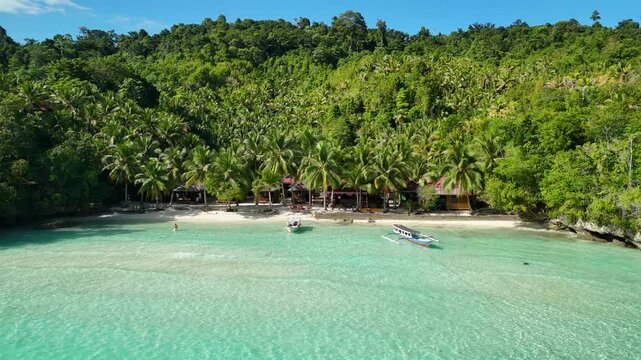INDONESIA - 9.4.2024 - Very good aerial view of tourists swimming and boating off the shore of Indonesia's tree-covered Malenge Island.