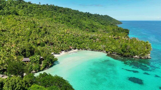 INDONESIA - 9.4.2024 - Amazing aerial footage circling down towards the shoreline of Indonesia's tree-covered Malenge Island.