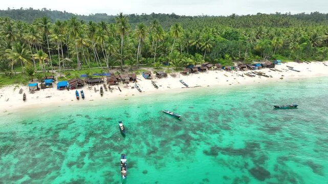 INDONESIA - 9.4.2024 - Fantastic aerial footage circling huts and small boats on a small section of Indonesia's palm tree-lined Mandel beach.