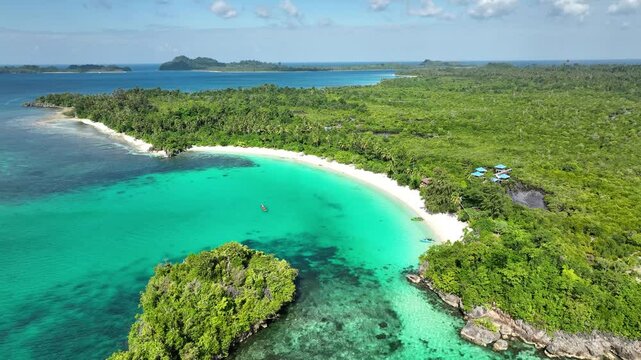 INDONESIA - 9.4.2024 - Fantastic aerial footage circling clockwise towards tourists boating off the coast of Indonesia's palm tree-lined Oyama Beach.