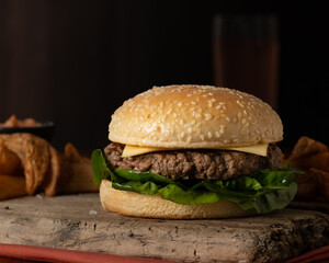 Hamburger with cheese and potato wedges with drink on background