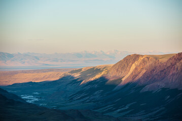 Fototapeta premium Scenic aerial top view to gold sheer crags on mountain ridge, illuminated by setting sun under clear sky in golden sunset tones. Evening alpine landscape in sunset color. Light and shadow in mountains