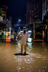 flood victims woman stands in the flooded streets of Chiang Mai city at night 2024, holding a bag...