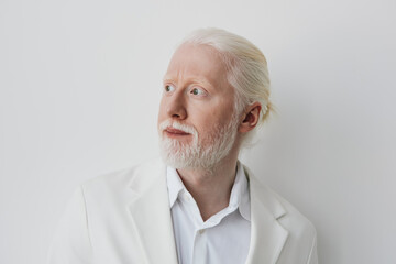 elderly man with white hair and beard in a stylish suit, looking to the side against a plain white background, expressing curiosity and confidence, ideal for conceptual themes of wisdom, experience