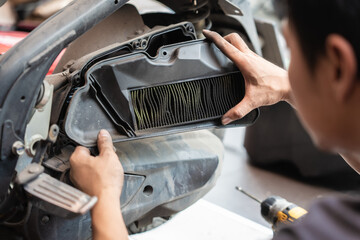 Obraz premium Mechanic holding dirty Engine Air Filter over motorcycle, working in motorcycle garage. Repair service and maintenance concept