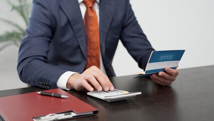通帳の金額を計算するビジネスマンの手元