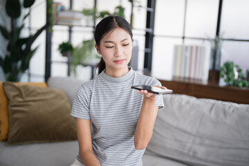 Asian woman using voice assistant on smartphone at home conversation with online assistant Voice...