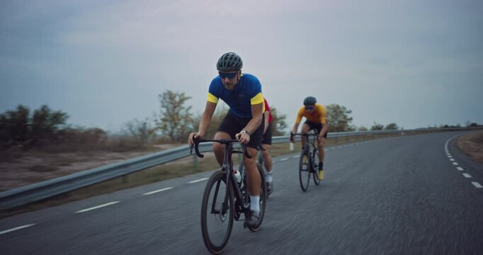 Riding in Formation, a Team of Three Cyclists Pushes Through the Road, Their Focus and Energy Undeterred by Bad Weather. Professional Rider Goes for an Overtake and Passes the Leading Athlete