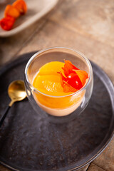 Traditional Italian dessert panna cotta with peaches in a glass, vertical photo