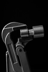 adjustable gas wrench on black background. Black and white photograph of a working tool