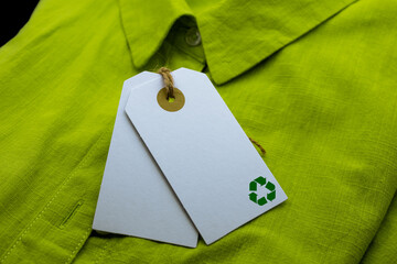 Abstract white paper blank tags tie with brown natural cord and recycle sign on green shirt. Ideal...