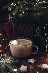 Cozy Christmas still life with hot chocolate, fir branches, Christmas cookies and lights.