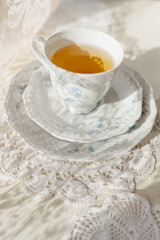 a tea cup stands with a saucer on a lace background