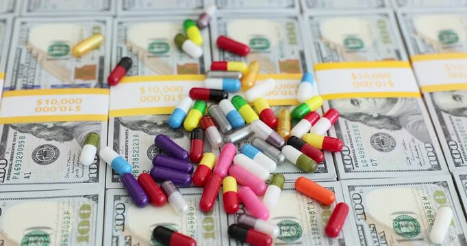 Hands holding medical pills over stacks of hundred dollar bills