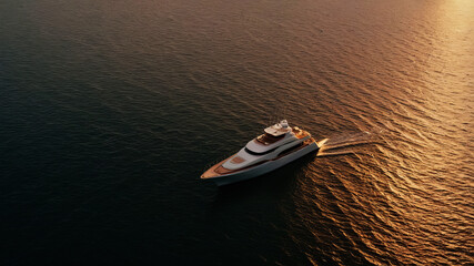 Aerial view of a yacht sailing in the sea to watch the sunset.