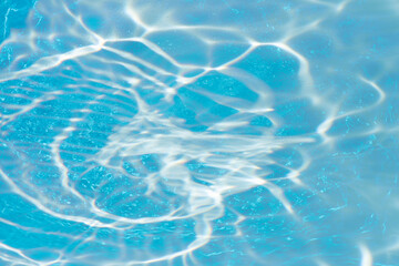 Blue water with ripples on the surface. Defocus blurred transparent blue colored clear calm water surface texture with splashes and bubbles. Water waves with shining pattern texture background.