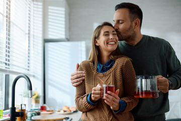 Affectionate couple enjoying in cup of tea in  kitchen.