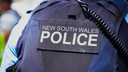 Sydney, NSW Australia - October 6 2024: crime in sydney. Close up of a NSW Police officers uniform sleeve patch and his communication device. australia police