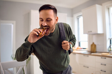 Mid adult man having quick snack while rushing to work.