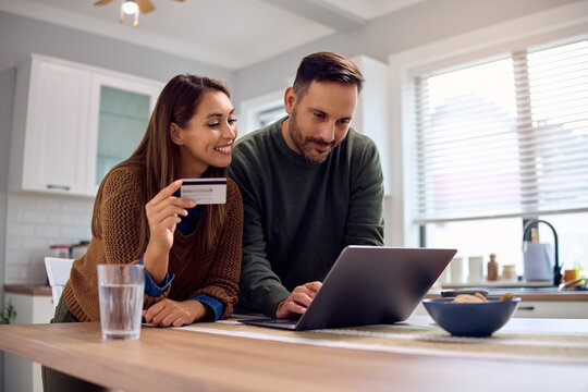 Happy couple using laptop and credit card while ordering online.