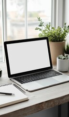 Fototapeta premium A laptop, notebook, pen, and plants on a desk.