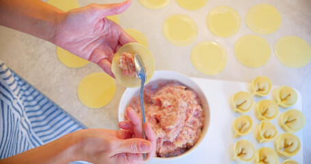 Woman Shaping Homemade Ravioli with Meat Filling in Kitchen