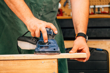 A person sanding with an electric sander.