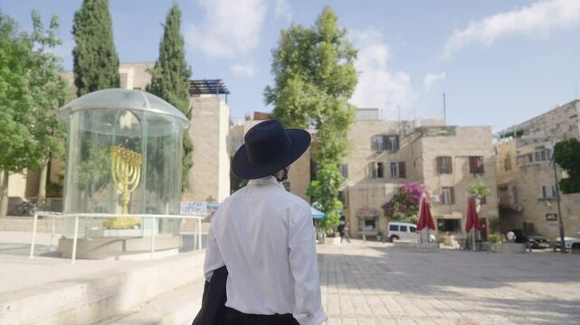 Orthodox Jew walking near candelabrum at Old City of Jerusalem, Israel