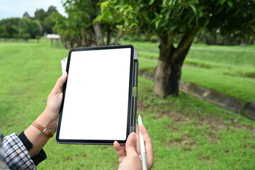 Modern farmer standing in field holding digital tablet with blank screen. Technology, innovation and farming concept
