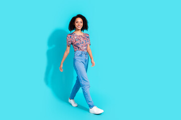 Full body photo of pretty young girl walking wear trendy colorful clothes isolated on aquamarine color background