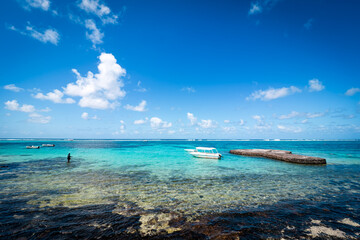 Beautiful postcard view of a tropical beach at Blue Bay, Mauritius, with coral reefs visible in the shallows of the crystal clear turquoise waters