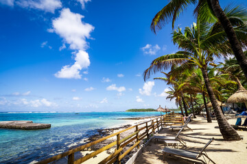 Beautiful postcard view of a tropical beach at Blue Bay, Mauritius, lined with coconut trees and crystal clear turquoise waters