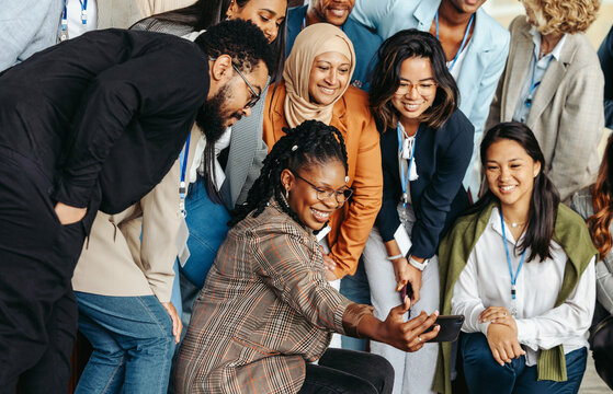 Diverse group of professionals taking a cheerful selfie together during a casual team meeting