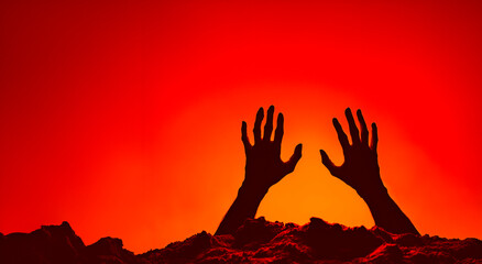 Obraz premium Spooky Halloween Scene: Silhouetted Hands Reaching Up Against Dramatic Orange and Red Sky - Eerie Holiday Vibes and Festive Atmosphere, copy space