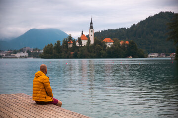 Man sitting on wooden deck, pier at Bled lake, Slovenia